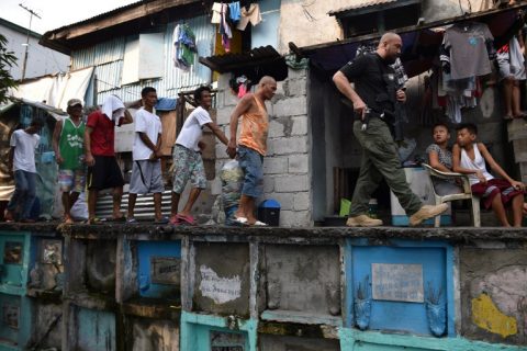 An agent (R) of Philippine Drug Enforcement Agency (PDEA) escorts suspects during a raid at an informal settlers' area inside a public cemetery in Manila on March 16, 2017. / AFP PHOTO / TED ALJIBE