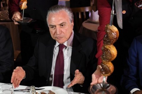 Brazilian President Michel Temer eats barbecue in a steak house in Brasilia after meeting with ambassadors from countries that import Brazilian meat, on March 19, 2017.  The revelation on Friday of a two-year police probe into alleged bribery of health inspectors to certify tainted food as fit for consumption has struck at the heart of the world's leading exporter of beef and chicken.  / AFP PHOTO / EVARISTO SA