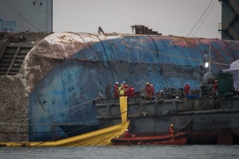 Workers aboard a Chinese salvage vessel participate in the salvage operation of the Sewol ferry off the coast of South Korea's southern island of Jindo on March 24, 2017. South Koreas sunken Sewol ferry emerged from the waters March 23, nearly three years after it went down with the loss of more than 300 lives and dealt a crushing blow to now-ousted president Park Geun-Hye. / AFP PHOTO / Ed JONES