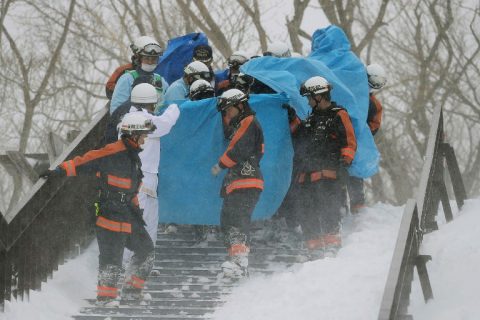 Firefighters carry a survivor they rescued from the site of an avalanche in Nasu town, Tochigi prefecture on March 27, 2017. Eight high school students were feared dead on March 27 after being engulfed by an avalanche while on a mountain-climbing outing with dozens of others, officials said. / AFP PHOTO / JIJI PRESS / JIJI PRESS / Japan OUT