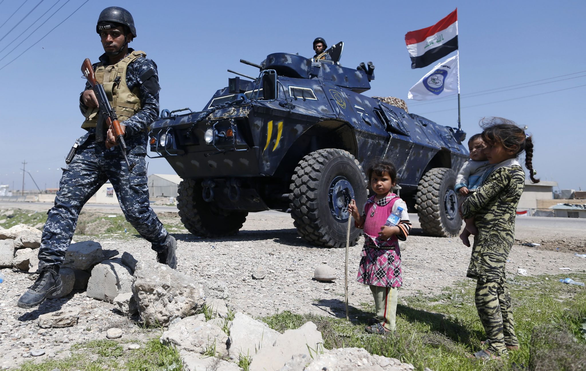 Displaced Iraqi children, who fled their homes in the Old City in western Mosul due to the ongoing fighting between government forces and Islamic State (IS) group fighters, are seen looking towards a security forces member ahead of being taken to the Hammam al-Alil camp, south of Mosul, on March 27, 2017. Iraqi forces renewed their assault against jihadists in Mosul's Old City, after days in which the battle was overshadowed by reports of heavy civilian casualties from air strikes. / AFP PHOTO / AHMAD GHARABLI