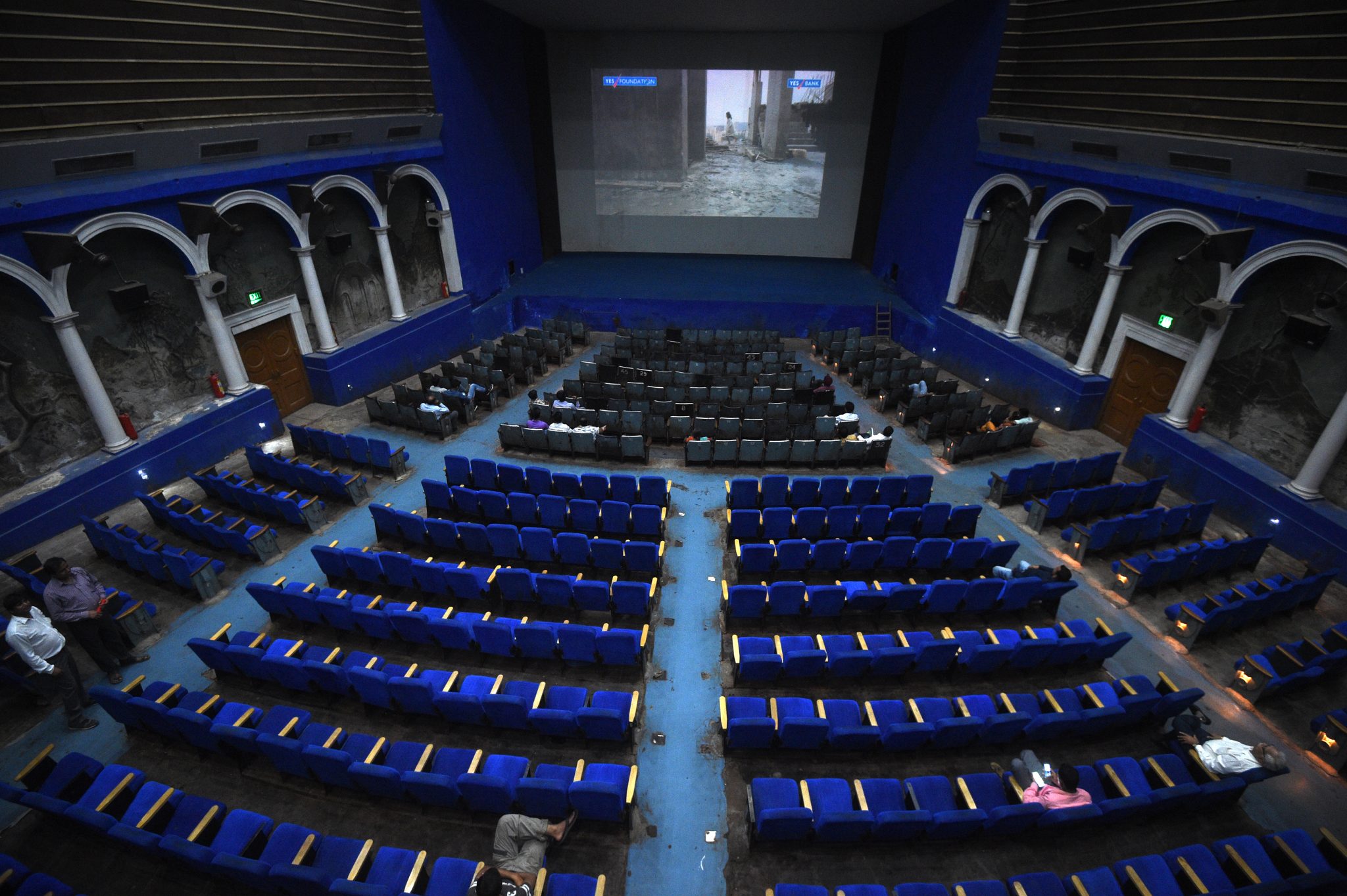 This picture taken on March 27, 2017 shows spectators waiting for a film showing at the Regal cinema, an 84-year-old movie hall, in the heart of the Indian capital New Delhi. After years of slow but steady decline the colonial-era Regal cinema, a New Delhi institution, is enjoying a late flourishing -- sadly just as it is about to close its doors. / AFP PHOTO / Dominique FAGET