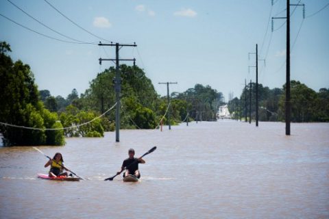 Kayakers paddle on the flooded Logan River, caused by Cyclone Debbie, as it flows over the Mt Lindesay Highway in Waterford West near Brisbane on April 1, 2017. Flooded rivers were still rising on April 1 in two Australian states with two women dead and four people missing after torrential rains in the wake of a powerful tropical cyclone. / AFP PHOTO / Patrick HAMILTON