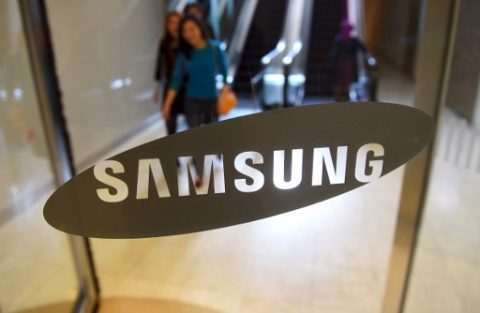 People walk past the logo of Samsung at a Samsung showroom in Seoul on April 7, 2017. Samsung Electronics said on April 7 it expects profits to soar by 48.2 percent in the first quarter despite a smartphone recall fiasco and the arrest of its de facto head. / AFP PHOTO / JUNG Yeon-Je