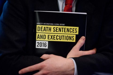 In this photo taken on April 10, 2017, a global report booklet by Amnesty International entitled 'Death Sentence and Execution' is held by James Lynch, deputy director of the Global Issues Programme at Amnesty International, after a media briefing at the Foreign Correspondents' Club (FCC) in Hong Kong.  China executed more people in 2016 than all other nations combined, Amnesty International said on April 11, 2017, as death penalties in the world decreased overall.  / AFP PHOTO / ANTHONY WALLACE