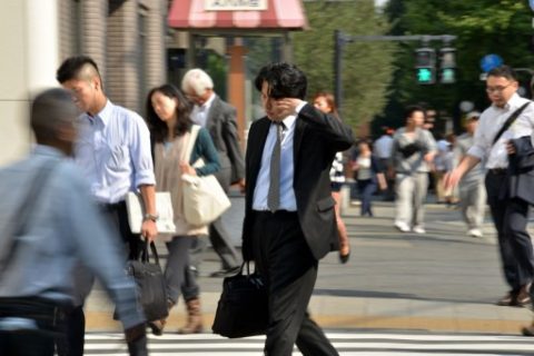 (FILES) This file photo taken on September 30, 2014 shows a Japanese businessman, called salaryman, rubbing his eyes as he heads to his office in Tokyo. Workaholic Japan has unveiled in March 2017 its first-ever plan to limit overtime, but critics want to give it the boot, saying an "outrageous" 100-hour-a-month cap will do nothing to tackle karoshi, or death from overwork. / AFP PHOTO / YOSHIKAZU TSUNO