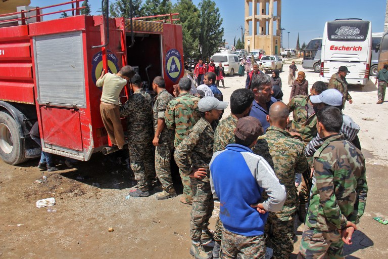 Syrians pro-government fighters and civilians, from the government-held towns of Fuaa and Kafraya, which have been under a crippling siege for more than two years, gather for water rations being distributed from a fire engine at the rebel-held transit point of Rashidin outside the government-held second city of Aleppo, on April 20, 2017, as they wait for the resumption of the evacuation. / AFP PHOTO / Omar haj kadour