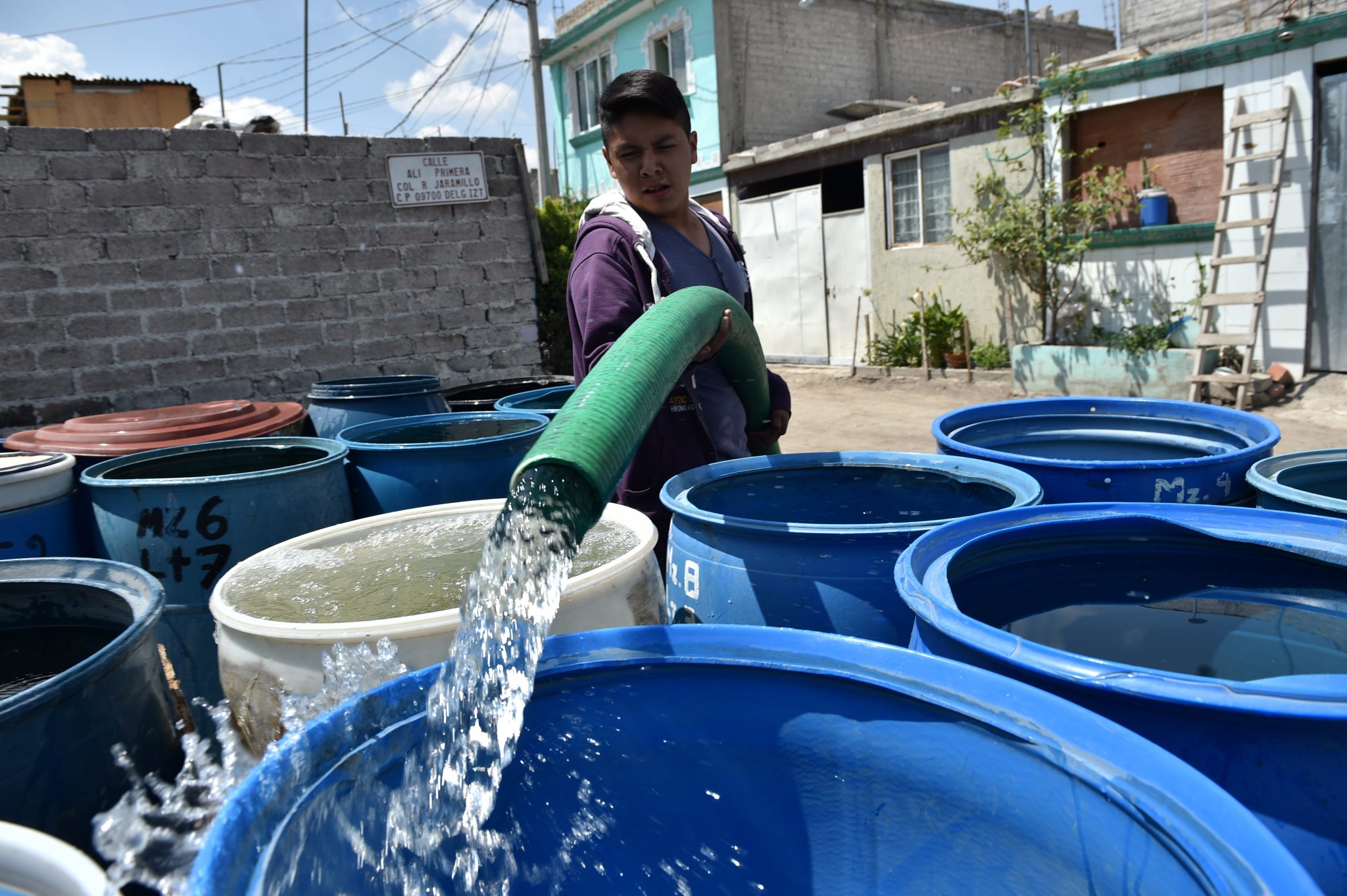A municipal employee fills barrels of water from a tanker truck in a neighborhood in the Mexico City borough of Iztapalapa on April 19, 2017. Dozens of municipal tanker trucks in Mexico City distribute water in neighborhoods that do not receive piped water. In Iztapalapa approximately two million people have no running water and have to fill barrels and carry it to their homes in buckets. / AFP PHOTO / YURI CORTEZ / TO GO WITH AFP STORY BY YUSSEL GONZALEZ