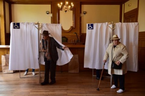 People leave voting booths at a polling station at the city hall of the 7th district in Paris, on April 23, 2017, during the first round of the Presidential elections. / AFP PHOTO / CHRISTOPHE ARCHAMBAULT
