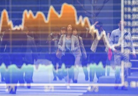 Pedestrians are reflected on the window of an electronic share indicator at a securities company in Tokyo on April 24, 2017. The Nikkei 225 rose 1.34 percent, or 249.49 points, to sit at 18,870.24 by the lunch break, as investors cheered news that market-friendly Emmanuel Macron is leading far-right candidate Marine Le Pen in the French presidential race. / AFP PHOTO / Toshifumi KITAMURA