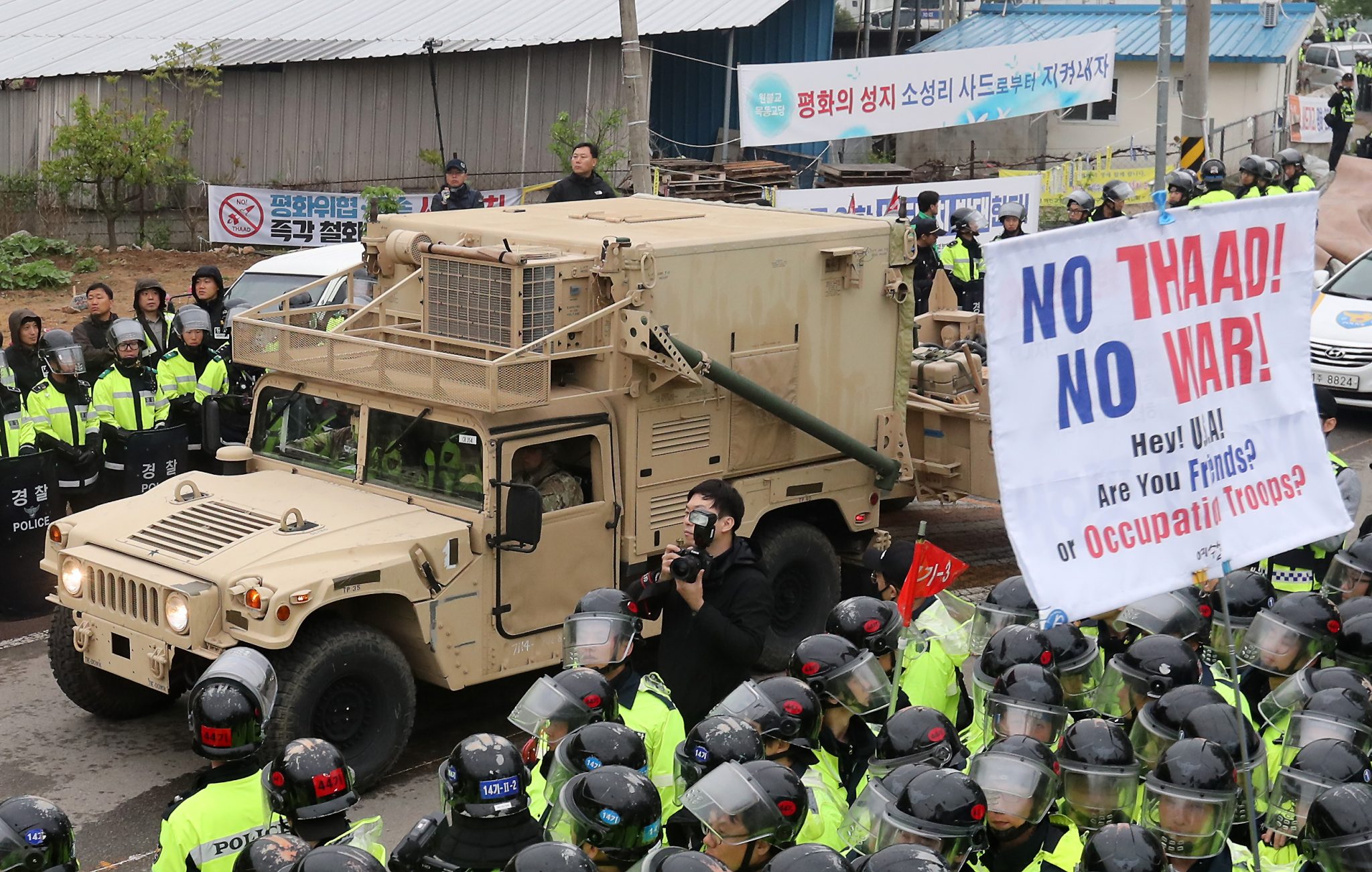 Protesters and police stand by as trailers carrying US THAAD missile defence equipment enter a deployment site in Seongju, early on April 26, 2017. Arrival of the six trailers at the golf course location sparked clashes between locals and police, the agency said. / AFP PHOTO / YONHAP / YONHAP / REPUBLIC OF KOREA OUT  NO ARCHIVES  RESTRICTED TO SUBSCRIPTION USE