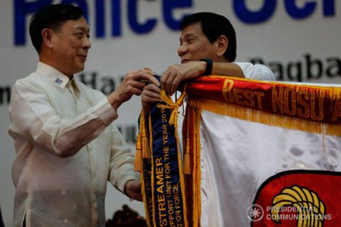 File photo of Acting Secretary of the Department of Interior and Local Government Catalino Cuy, who was also the undersecretary for peace and order, in August 2016, while assisting President Rodrigo R. Duterte, in tying a presidential streamer during the 115th Police Service Anniversary celebration at Camp Crame on August 17, 2016. TOTO LOZANO/PPD