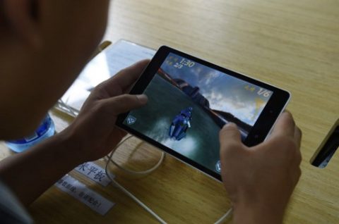 A customer plays a game on a Xiaomi Mi Pad tablet at a Xiaomi service center in Beijing on August 5, 2015. Chinese company Xiaomi was the largest smartphone vendor in China based on shipments with a 15.9 percent market share in the second quarter of 2015, according to Canalys. Telecom equipment maker Huawei was close behind at 15.7 percent, it said, followed by Apple, South Korea's Samsung and Chinese firm Vivo. AFP PHOTO / GREG BAKER / AFP PHOTO / GREG BAKER