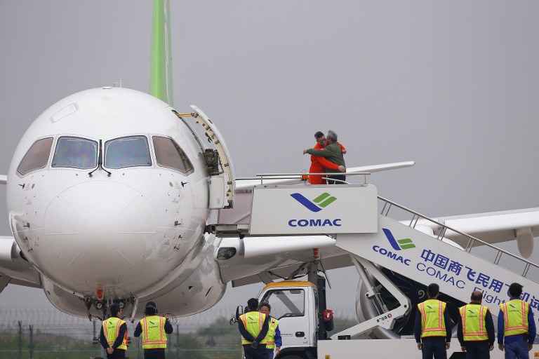 A member of staff is congratulated as he steps out of China's home-grown C919 passenger jet after its maiden flight at Pudong International Airport in Shanghai on May 5, 2017. The first large made-in-China passenger plane took off on its maiden test flight on May 5, marking a key milestone on the country's ambitious journey to compete with the world's leading aircraft makers. / AFP PHOTO / POOL / ALY SONG
