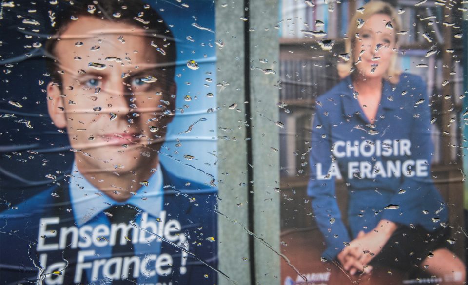 The posters of second round French Presidential elections candidates for the far-right Front National party Marine Le Pen (R) and for the En Marche ! movement Emmanuel Macron are seen through the wet windshield of a car parked in the town of Bacqueville-en-Caux, in Normandy.  / AFP PHOTO / Mladen ANTONOV