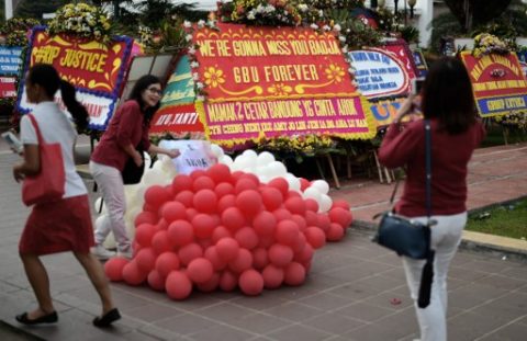An Indonesian takes a photograph next to farewell wreaths for Basuki Tjahaja Purnama also known as Ahok, Jakarta's first non-Muslim governor for half a century and its first ethnic Chinese leader, at cityhall in Jakarta, on May 10, 2017. Jakarta's Christian governor was jailed for two years after being found guilty of blasphemy, in a shock decision that has stoked concerns over rising religious intolerance in the world's most populous Muslim-majority nation. / AFP PHOTO / BAY ISMOYO