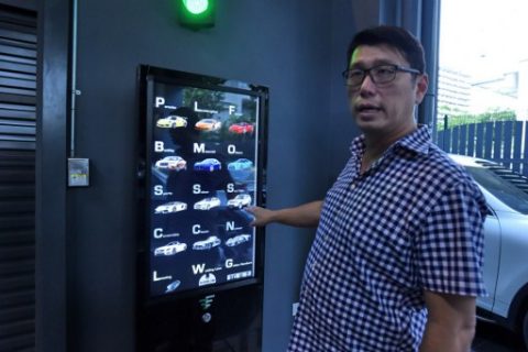 This photograph taken on May 18, 2017 shows used car dealer Gary Hong showing the selection buttons for luxury supercars displayed inside the AutoBahn Motors (ABM) building in Singapore. A vending machine that dispenses luxury cars to well-heeled buyers is the latest space-saving innovation in land-starved Singapore -- just don't try to shake it if it gets stuck. / AFP PHOTO / ROSLAN RAHMAN