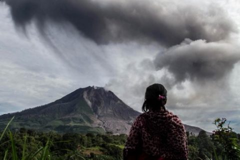 A villager looks on as Mount Sinabung volcano spews thick volcanic ash, as seen from Beganding village in Karo, North Sumatra province, on May 19, 2017.  Sinabung roared back to life in 2010 for the first time in 400 years. After another period of inactivity, it erupted once more in 2013 and has remained highly active since. / AFP PHOTO / Ivan DAMANIK