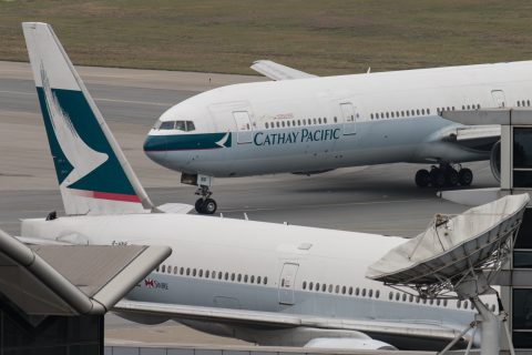 (FILES) In this file photo taken on March 15, 2017 a Cathay Pacific Boeing 777 passenger aircraft (top) taxis past a stationary plane on the tarmac at the international airport in Hong Kong. Hong Kong's flagship airline Cathay Pacific said on May 22, 2017 it would cut 600 staff as part of a major overhaul to slash costs and repair its bottom line. / AFP PHOTO / Anthony WALLACE
