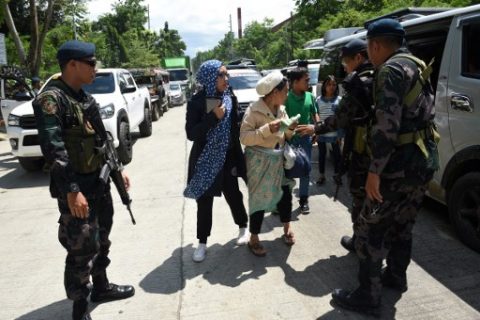 Philippine policemen check evacuees from Marawi aboard a van at a checkpoint by the entrance of Iligan City, in southern island of Mindanao on May 24, 2017. Philippine President Rodrigo Duterte warned that martial law would be "harsh" and like a dictatorship, after imposing military rule in the south of the country to combat Islamist militants. / AFP PHOTO / TED ALJIBE