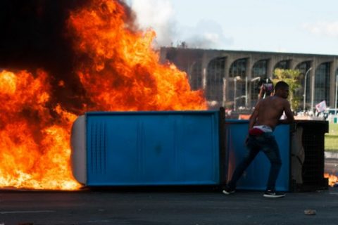 Demonstrators light a chemical bathroom during the protest "Occupy Brasilia" against the labor and social security reforms and the government of President Michel Temer in Brasilia, on May 24, 2017. / AFP PHOTO / Andressa Anholete