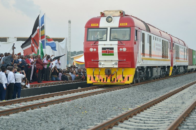 Kenyan President Uhuru Kenyatta flags off a cargo train as it leaves the container terminal at the port of the coastal town of Mombasa on May 30, 2017. More than a century after a colonial railway gave birth to modern Kenya, the country is betting on a new Chinese-built route to cement its position as the gateway to East Africa. The $3.2 billion (2.8 billion euro) railway linking Nairobi with the port city of Mombasa will May 31 take its first passengers on the 472 kilometre (293 mile) journey, allowing them to skip a hair-raising drive on one of Kenya's most dangerous highways. / AFP PHOTO / TONY KARUMBA