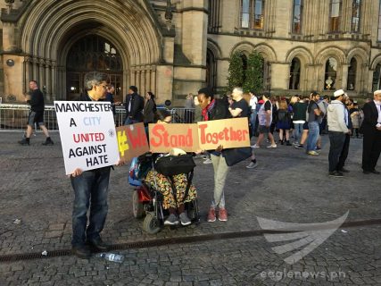 People hold signs declaring their unity against violence and hate in Manchester, England following the suicide blast attack at the Manchester Arena just before the closing of the Ariana Grande concert.  At least 22 people were killed, including children and their parents.  (Eagle News Service, Photo by EBC London Bureau)