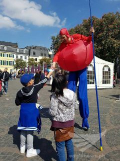 These kids, hand out pamphlets of the Iglesia Ni Cristo (Church of Christ) to a man in stilts and a costume in Bonn, Germany during the Europe Day observance. (Photo by Gemma Tropel, Eagle News Service Germany)