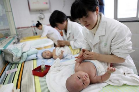 This photograph taken on December 15, 2016, shows nurses massaging babies at an infant care centre in Yongquan, in Chongqing municipality, in southwest China.  China had one million more births in 2016 than in 2015, following the end of the one-child policy at the end of 2015. / AFP PHOTO / STR