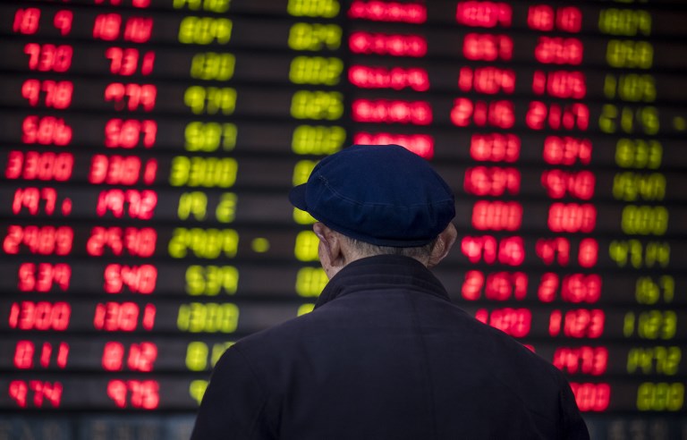 FILE PHOTO: An investor looks at an electronic board showing stock information at a brokerage house in Shanghai on March 16, 2017. / AFP PHOTO / Johannes EISELE