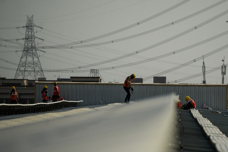 In this photograph taken on May 16, 2017, Indian labourers install solar panels at a site in Greater Noida, some 45km east of the capital New Delhi. Solar power prices in India have hit rock bottom, but it is not all good news for the electricity-starved country as the phenomenon has hit investor confidence and threatens the country's effort to push its green credentials. / AFP PHOTO / CHANDAN KHANNA / TO GO WITH AFP STORY INDIA-ENERGY-SOLAR-ECONOMY, FOCUS by MEGHA BAHREE