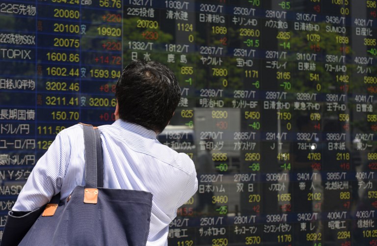 A man looks at a stock quotation board of the Tokyo Stock Exchange in front of a securities company in Tokyo on June 2, 2017. Tokyo shares opened higher June 2 after a record close on Wall Street following a batch of mostly strong economic data that raised expectations for a looming US jobs report. / AFP PHOTO / Kazuhiro NOGI