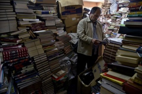 Jose Alberto Gutierrez checks books stacked in his library on the first floor of his house in Bogota, on May 18, 2017. Bogota has who rescues its books. For more than two decades Jose Alberto Gutierrez - "The Lord of Books", as he is known in Colombia - drives a garbage truck through the gray and cold streets of Bogota. In addition to wastes, he has collected thousands of books that crowded into his home, converted into a free library. / AFP PHOTO / GUILLERMO LEGARIA
