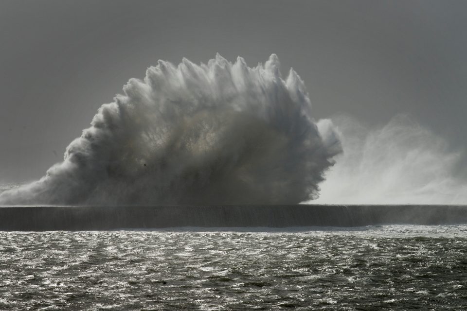 Waves break over a sea wall at Cape Town harbour on June 7, 2017, as an intense storm hits South Africa's west coast. The ferocious storm killed eight people as it pummelled South Africa's west coast on Wednesday, forcing the closure of Cape Town harbour, triggering flash floods and causing extensive damage, authorities said. The weather system which struck on June 6 has damaged buildings, felled trees, left 46,000 homes without electricity and caused travel chaos as flights and rail services were hit by gale-force winds and flooding. / AFP PHOTO / RODGER BOSCH