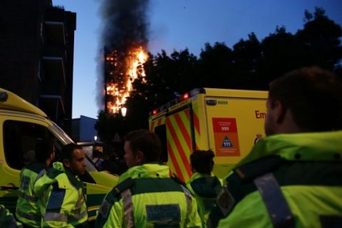 Members of the emergency services watch as Grenfell Tower is engulfed by fire on June 14, 2017 in west London.  The massive fire ripped through the 27-storey apartment block in west London in the early hours of Wednesday, trapping residents inside as 200 firefighters battled the blaze. Police and fire services attempted to evacuate the concrete block and said "a number of people are being treated for a range of injuries", including at least two for smoke inhalation.   / AFP PHOTO / Daniel LEAL-OLIVAS