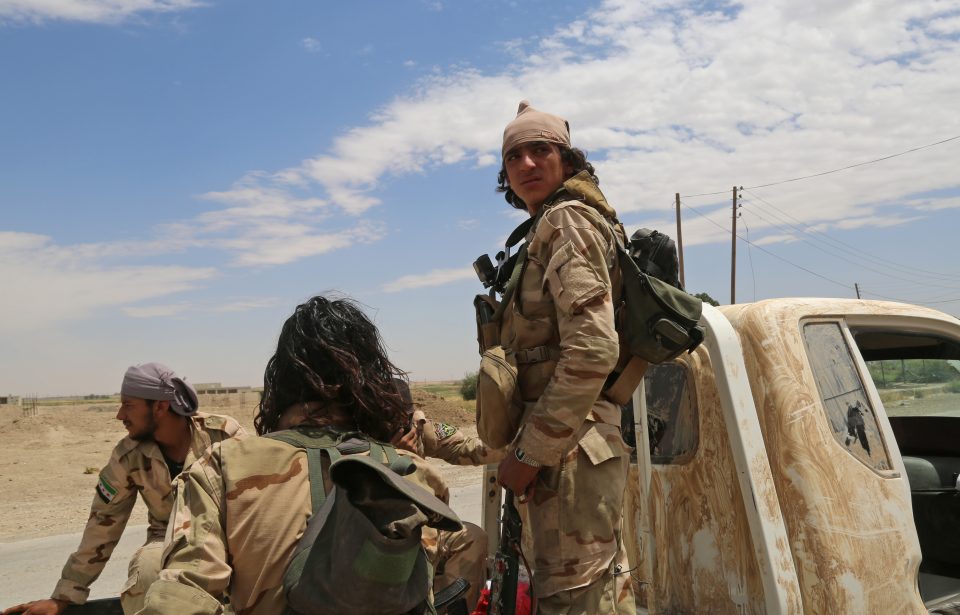 Opposition members of Ahmad Jarba's Syrian Elite Forces, fighting alongside the Syrian Democratic Forces (SDF), ride a truck in a neighbourhood on the eastern front of the Islamic State (IS) group's Syrian bastion of Raqa during an offensive to retake the city from the jihadists on June 14, 2017. / AFP PHOTO / DELIL SOULEIMAN
