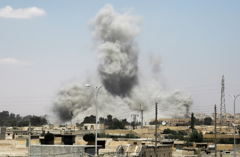 Smoke billows from buildings in the northern Syrian city of Raqa on June 18, 2017, during an offensive by US-backed fighters to retake the Islamic State (IS) group bastion. / AFP PHOTO / DELIL SOULEIMAN