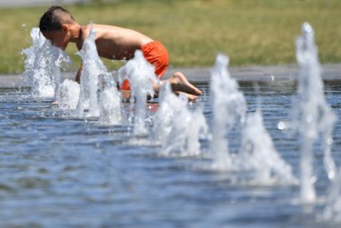 A boy refreshes himself in the water of a public fountain as Meteo France has placed 16 departments on orange alert for heatwaves on June 19, 2017 in Nantes, western France.   / AFP PHOTO / LOIC VENANCE