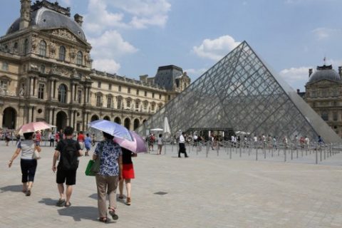 Pedestrians use umbrellas to shield themselves from the sun near The Louvre Museum in Paris on June 21, 2017, as temperatures climb across Europe. Europe continued to sizzle in a continent-wide heatwave, with London bracing for Britain's hottest June day since 1976 as Portugal battled to stamp out deadly forest fires. / AFP PHOTO / LUDOVIC MARIN