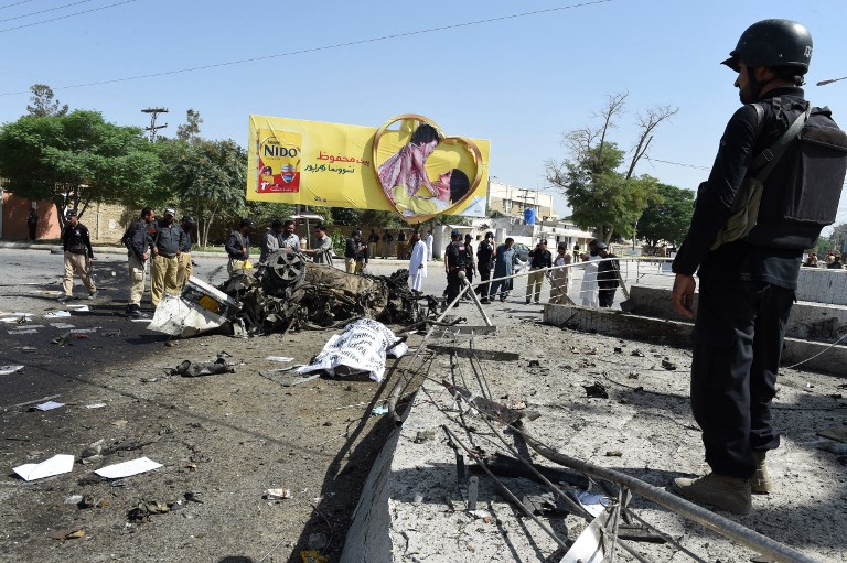 EDITORS NOTE: Graphic content / A body is covered at the site of an explosion as Pakistani security officials stand guard in Quetta on June 23, 2017. An explosion targeting a police vehicle in Pakistan's southwestern Quetta city on June 23 killed at least five people and injured 14 others, officials said. The explosion occurred in front of the office of the police chief in Quetta city, which is capital of the mineral rich southern Balochistan province rife with the separatist and Islamist insurgencies. / AFP PHOTO / BANARAS KHAN