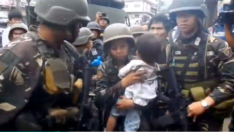 A baby is held tightly by a woman soldier on Sunday. The baby is among the six civilians rescued during the eight-hour humanitarian pause in respect for the end of the Muslim's Ramadan. (Photo grabbed from Reuters video)